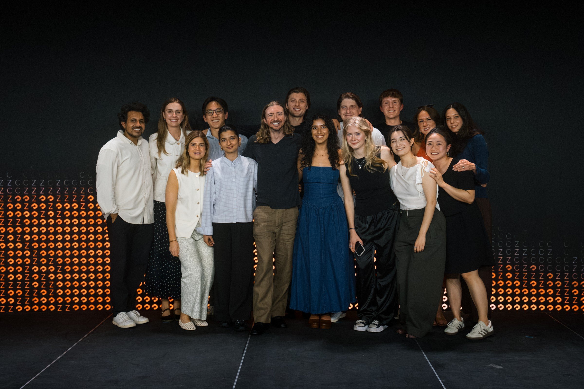 The Profound team posing together on a dark stage in front of an orange dotted backdrop