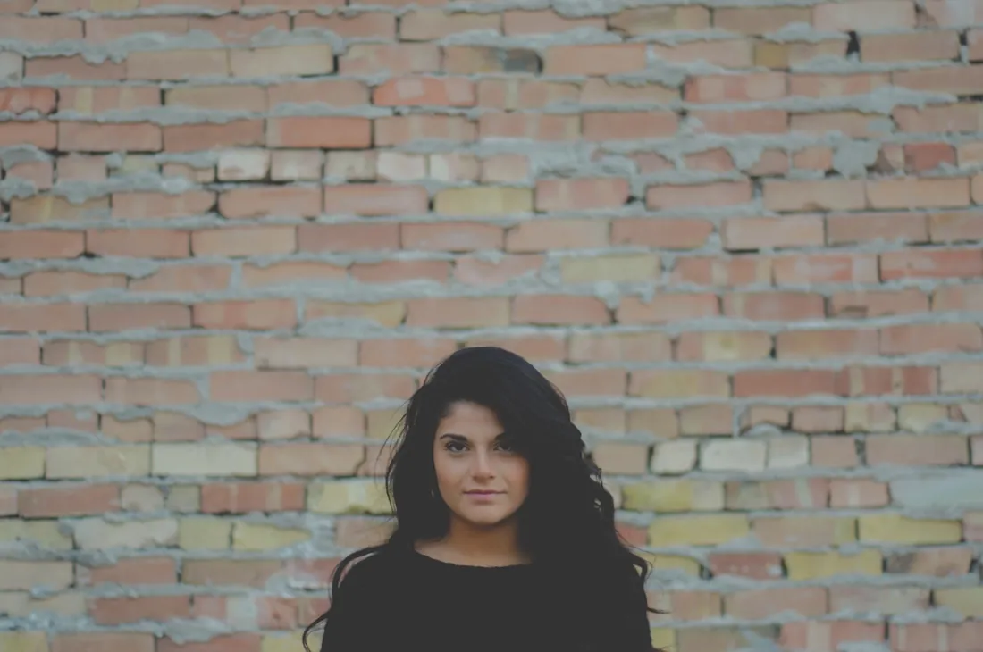 Portrait of a woman in front of a red brick wall