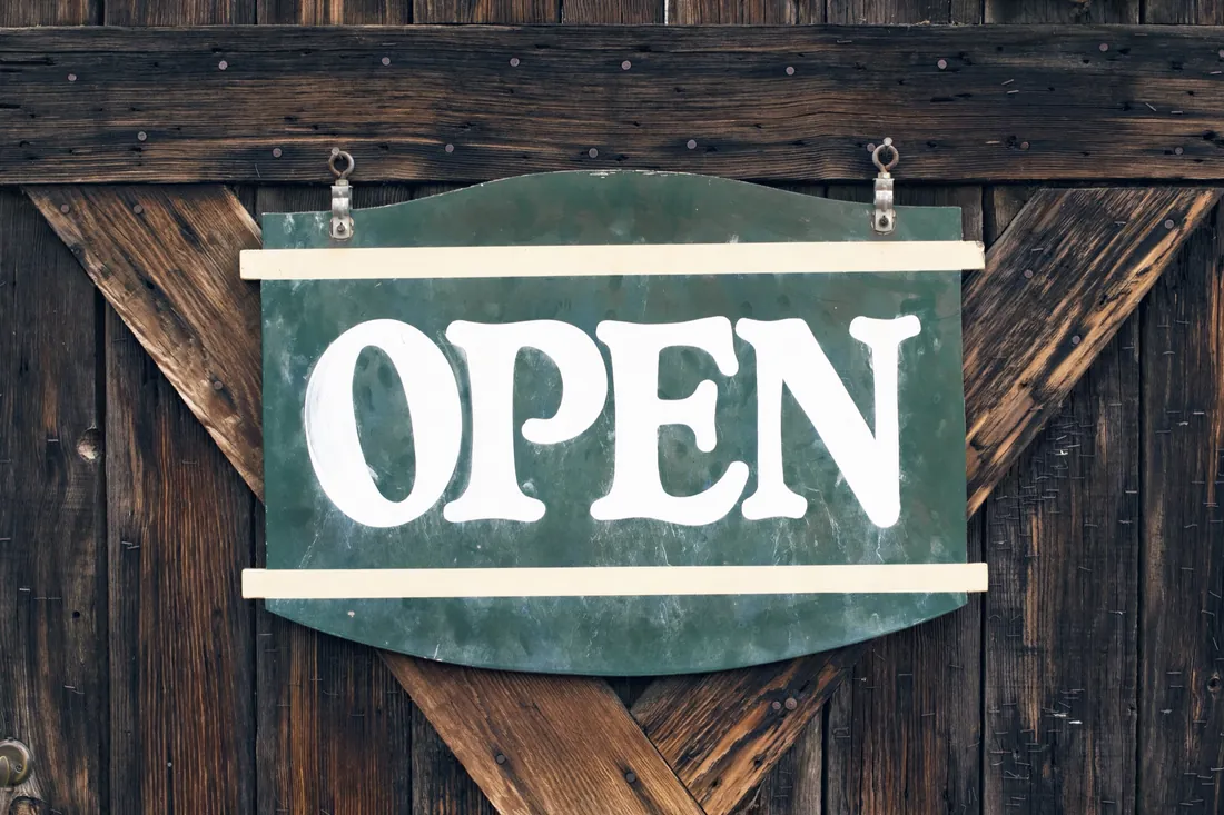 Green hand-painted OPEN sign on a wooden barn door